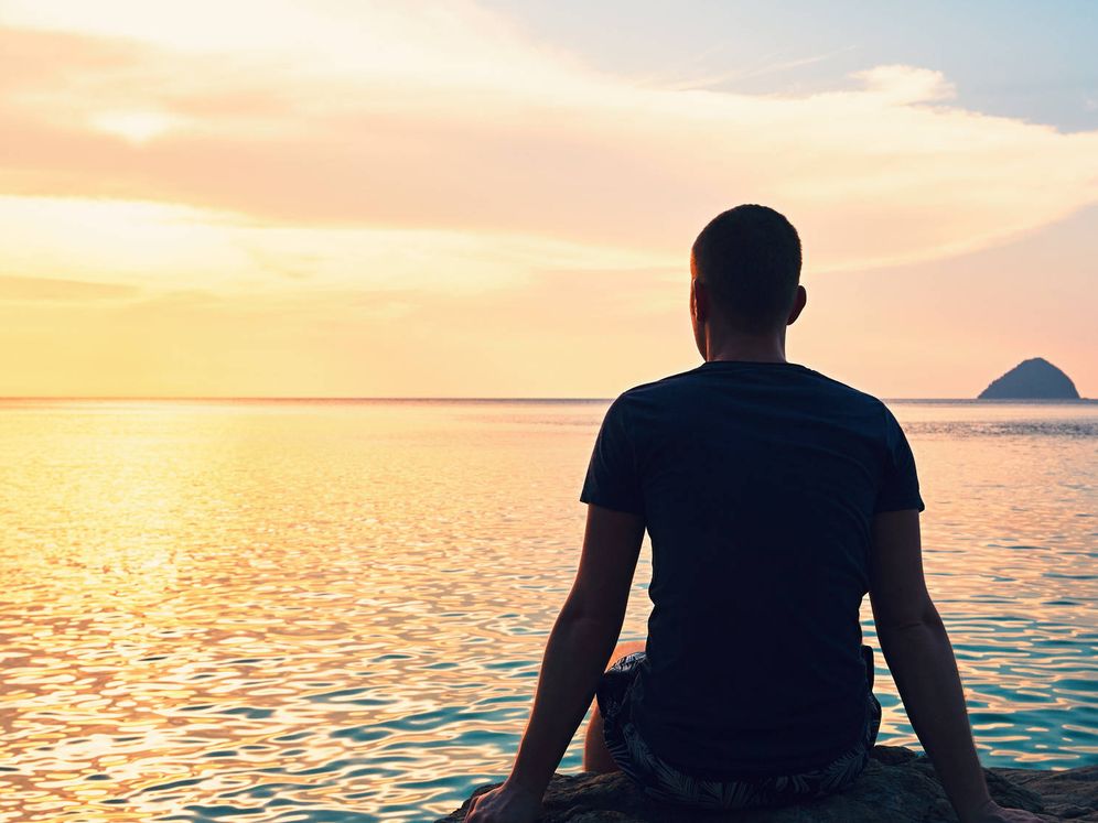Persona sola che guarda l’orizzonte al tramonto